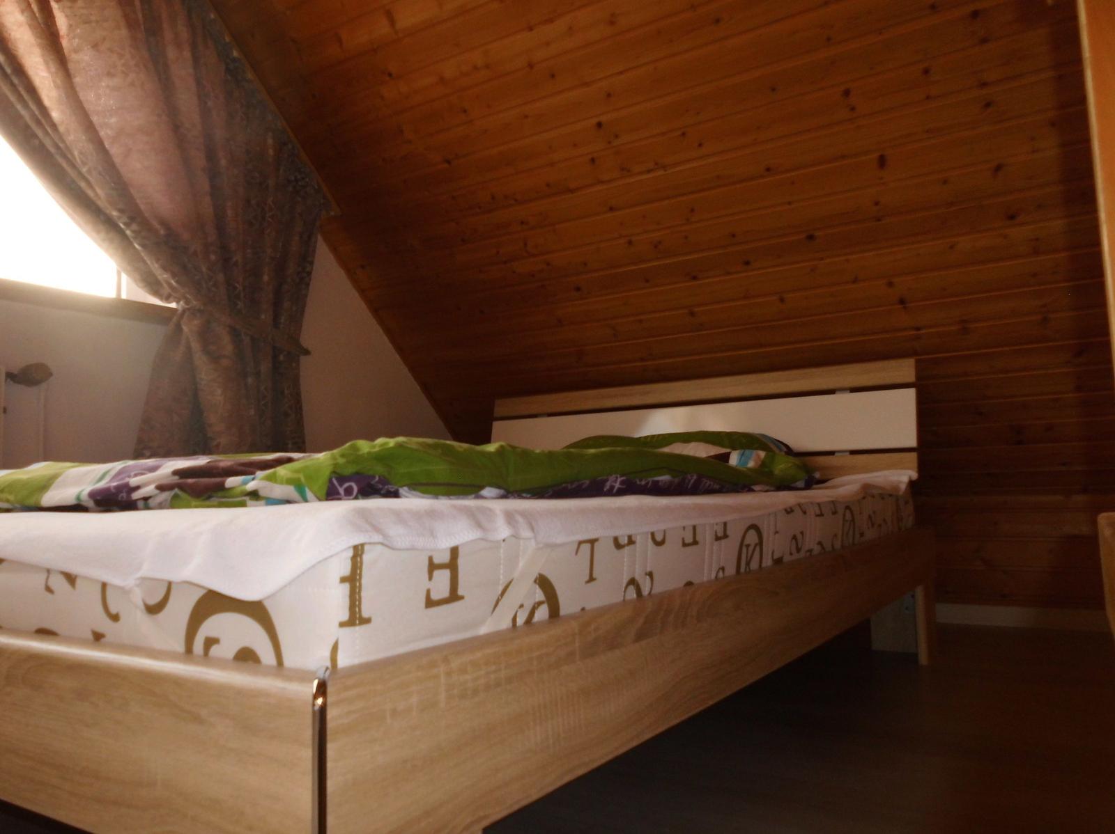Bedroom with wooden ceiling and bed with bedding.
