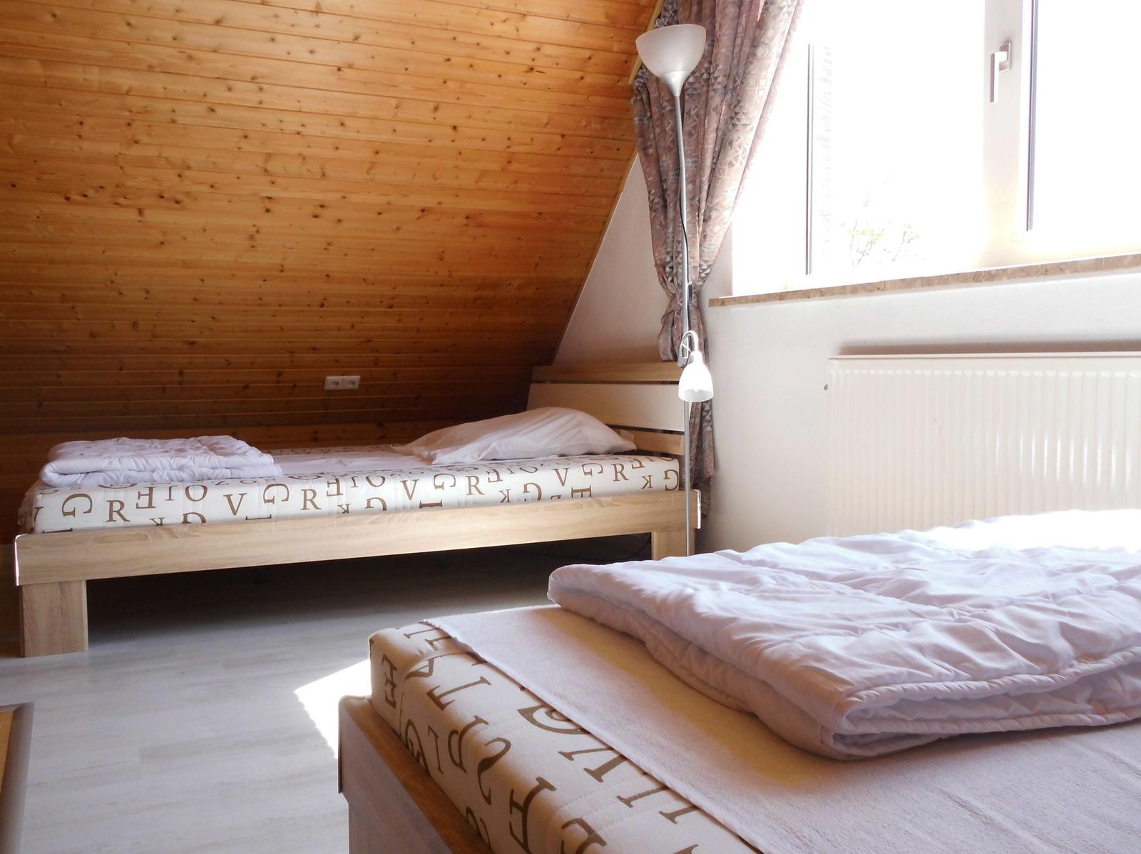 Two beds with bedding, wooden wall and window
