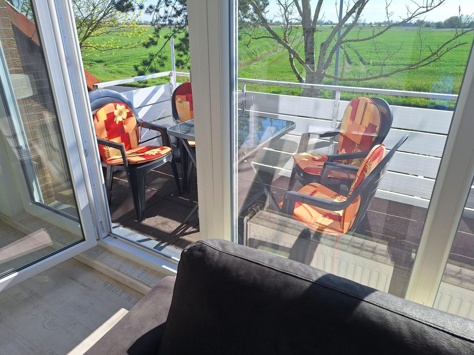 Terrace with seating area and view of green fields.
