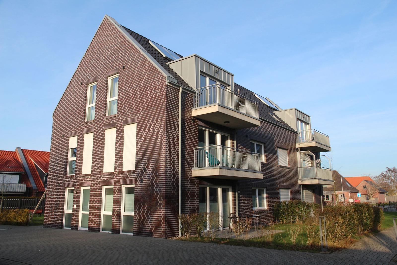 Moderne Mehrfamilienhaus mit Balkonen und Ziegelfassade.