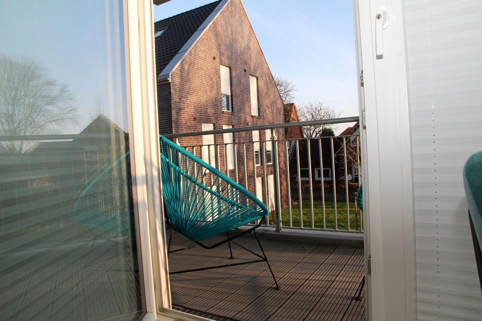 Terrasse mit blauer Sitzgelegenheit und Blick auf ein Haus.