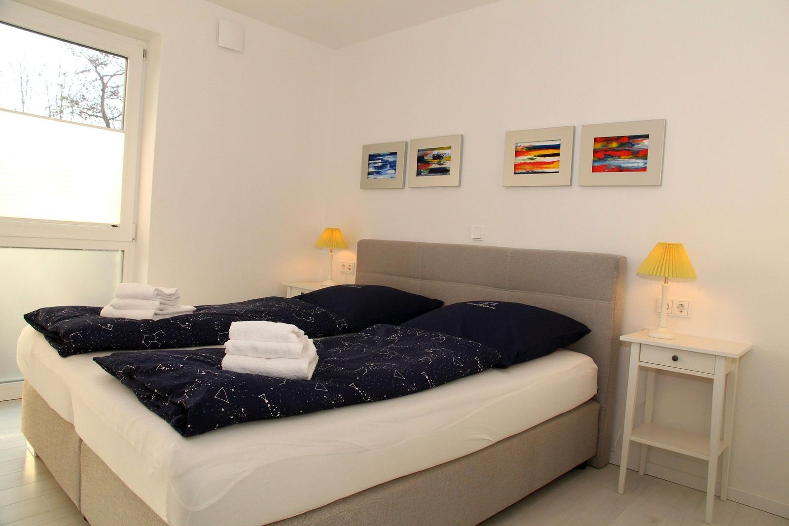 Schlafzimmer mit Doppelbett, Nachttischen und Fenster.