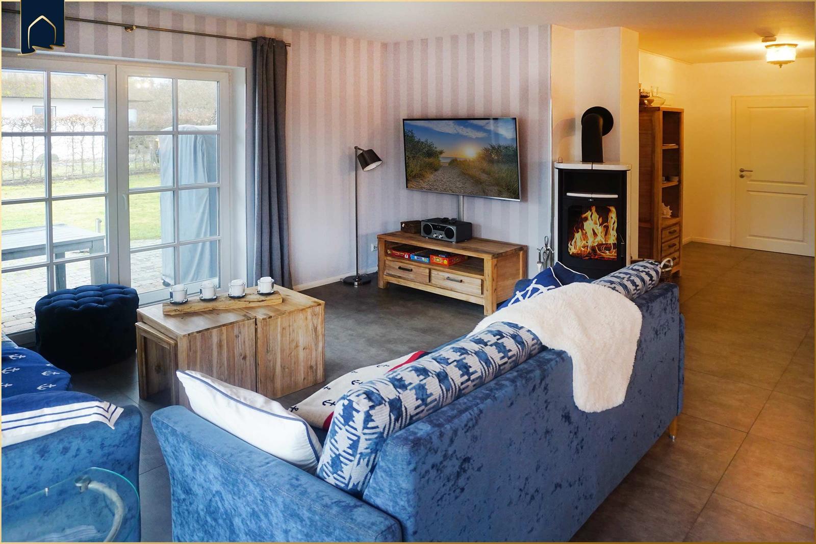 Wohnzimmer mit Kamin, Sofa und TV. Durchgang zur Terrasse.