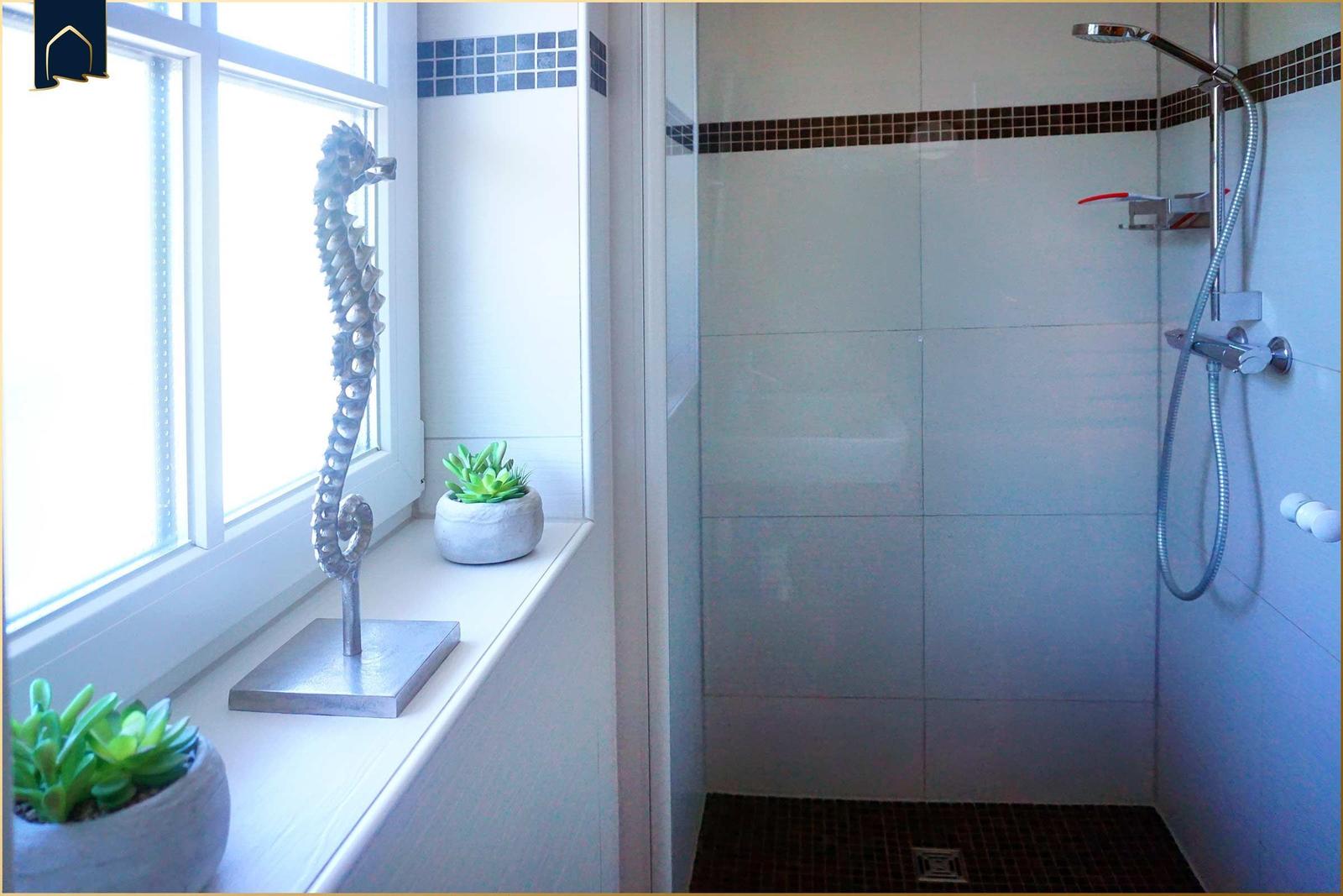 Bad mit Dusche, Fenster und Dekoration.