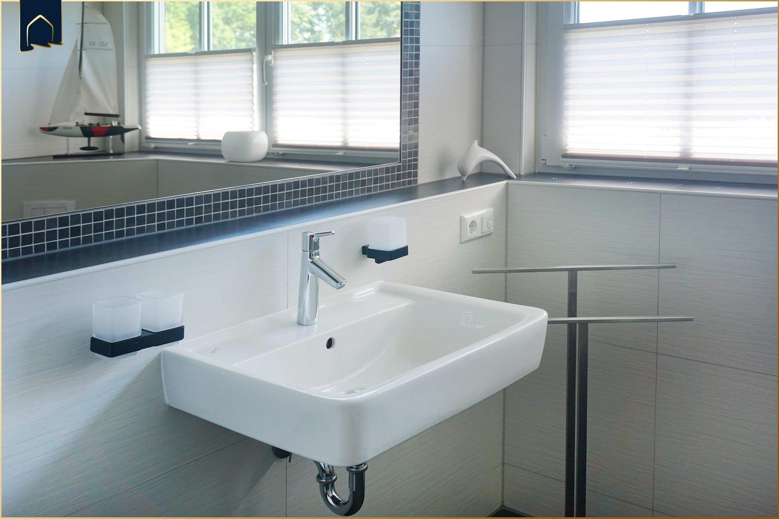 Waschbecken mit Spiegel und Fenster im Badezimmer