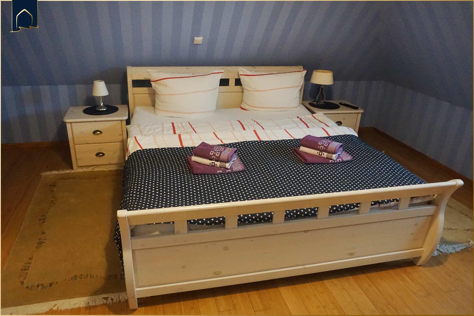 Ein Schlafzimmer mit einem Bett, zwei Nachttischen und einer gemusterten Wand.