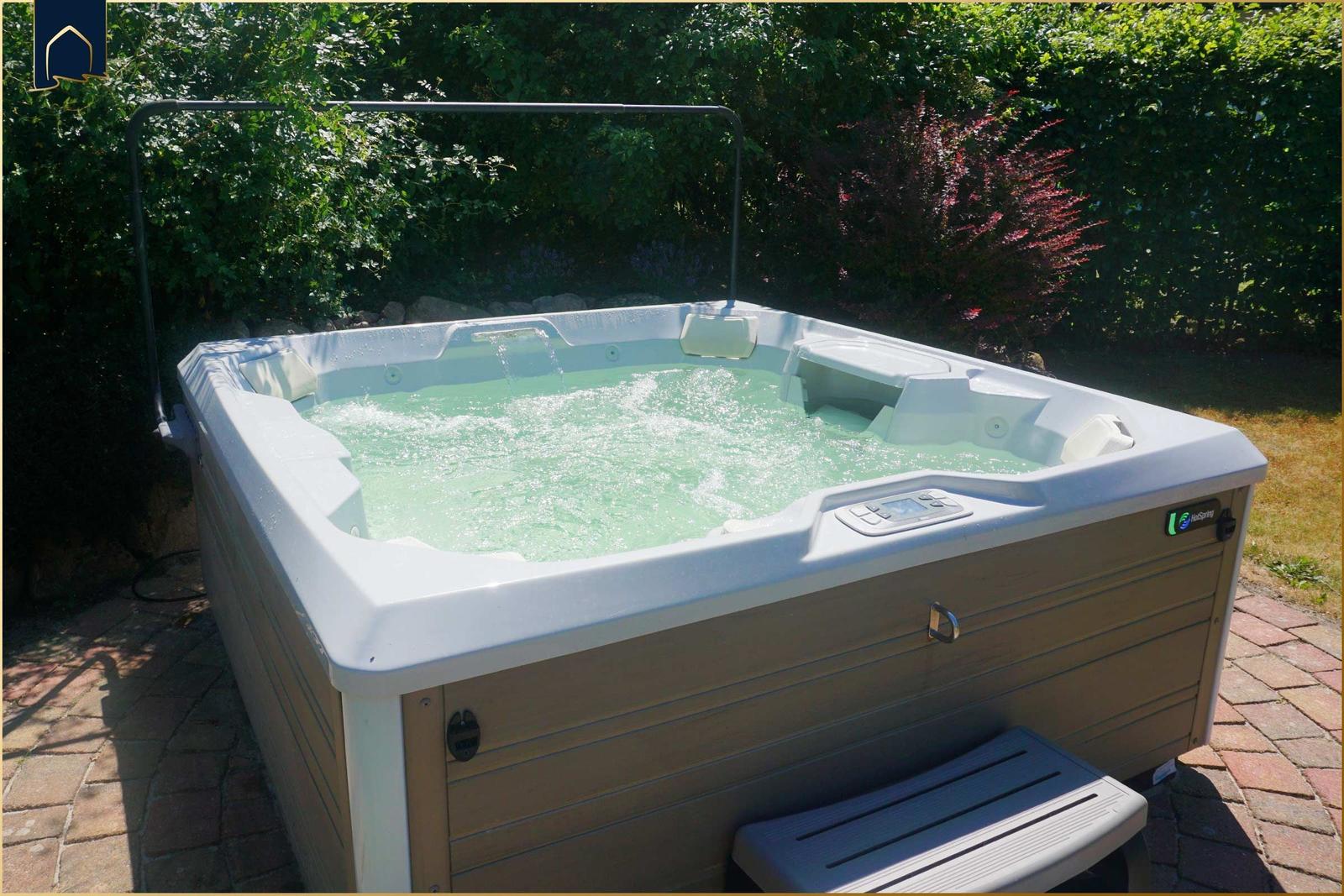 Ein Whirlpool mit Sprudelwasser steht auf einer Steinplattform umgeben von Bäumen.