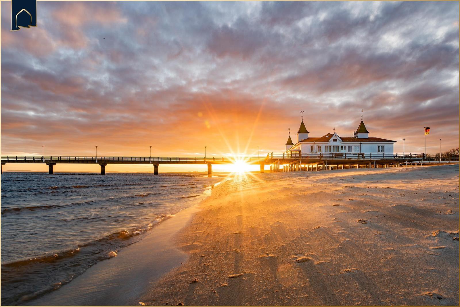 Sonnenuntergang am Strand mit Pier und Strandhaus.