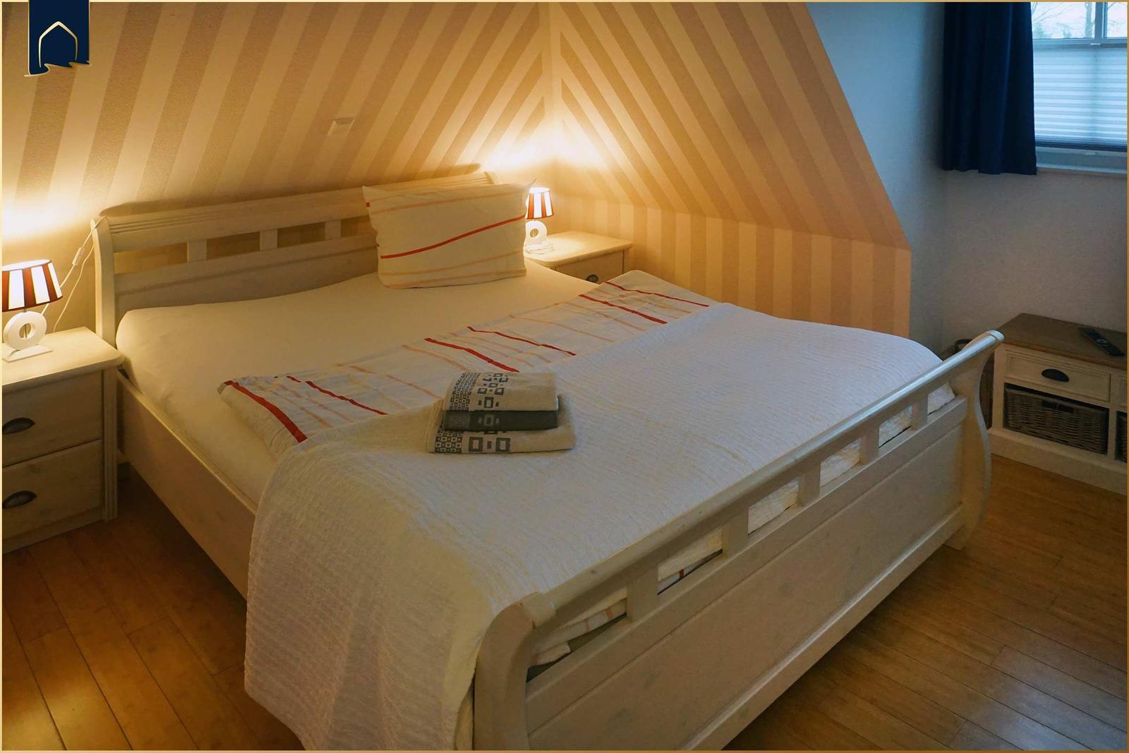 Schlafzimmer mit Bett, Nachttischen und Fenster