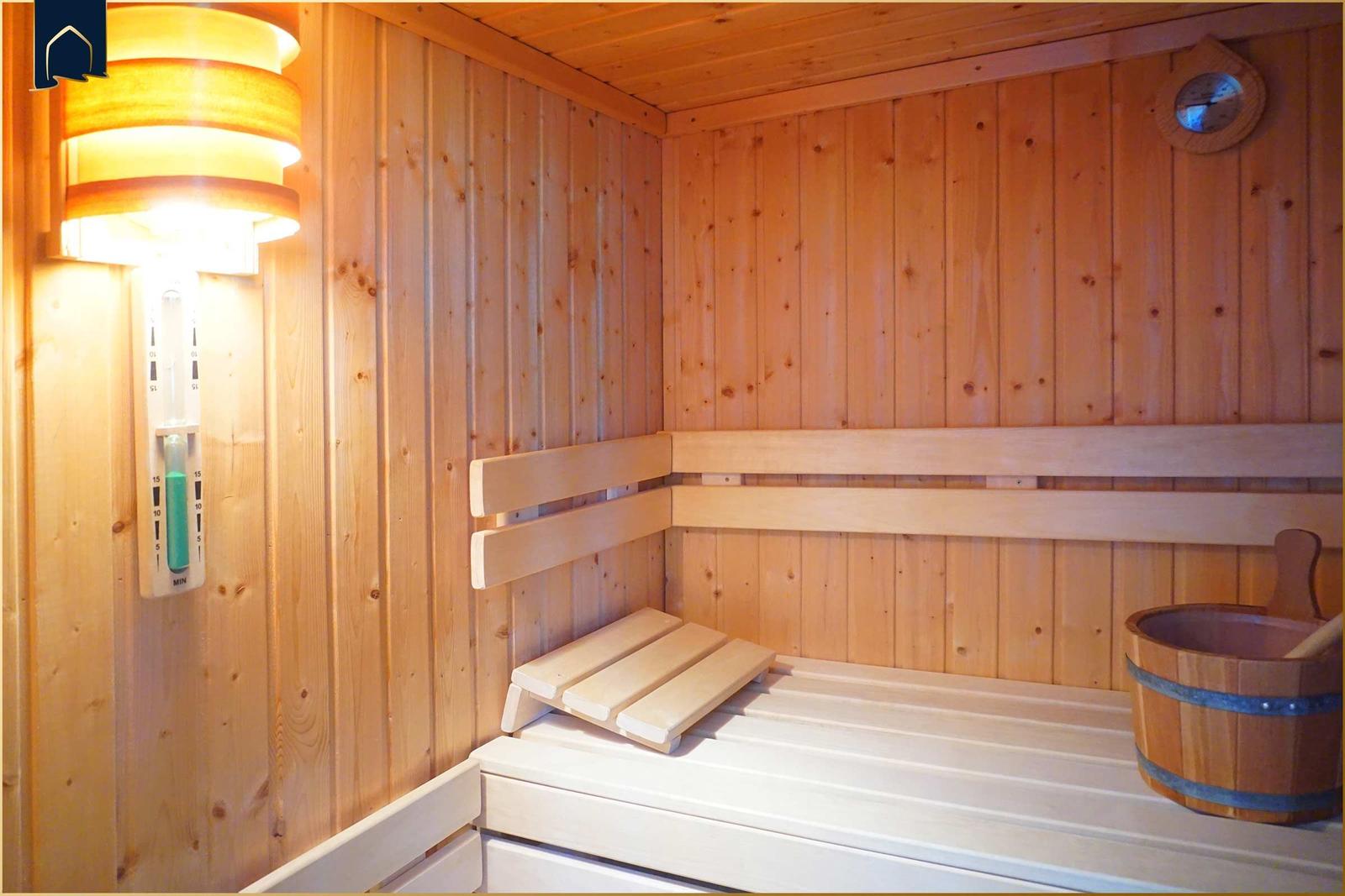 Sauna mit Holzwand, Sitzbank und Holzwaschbecken.