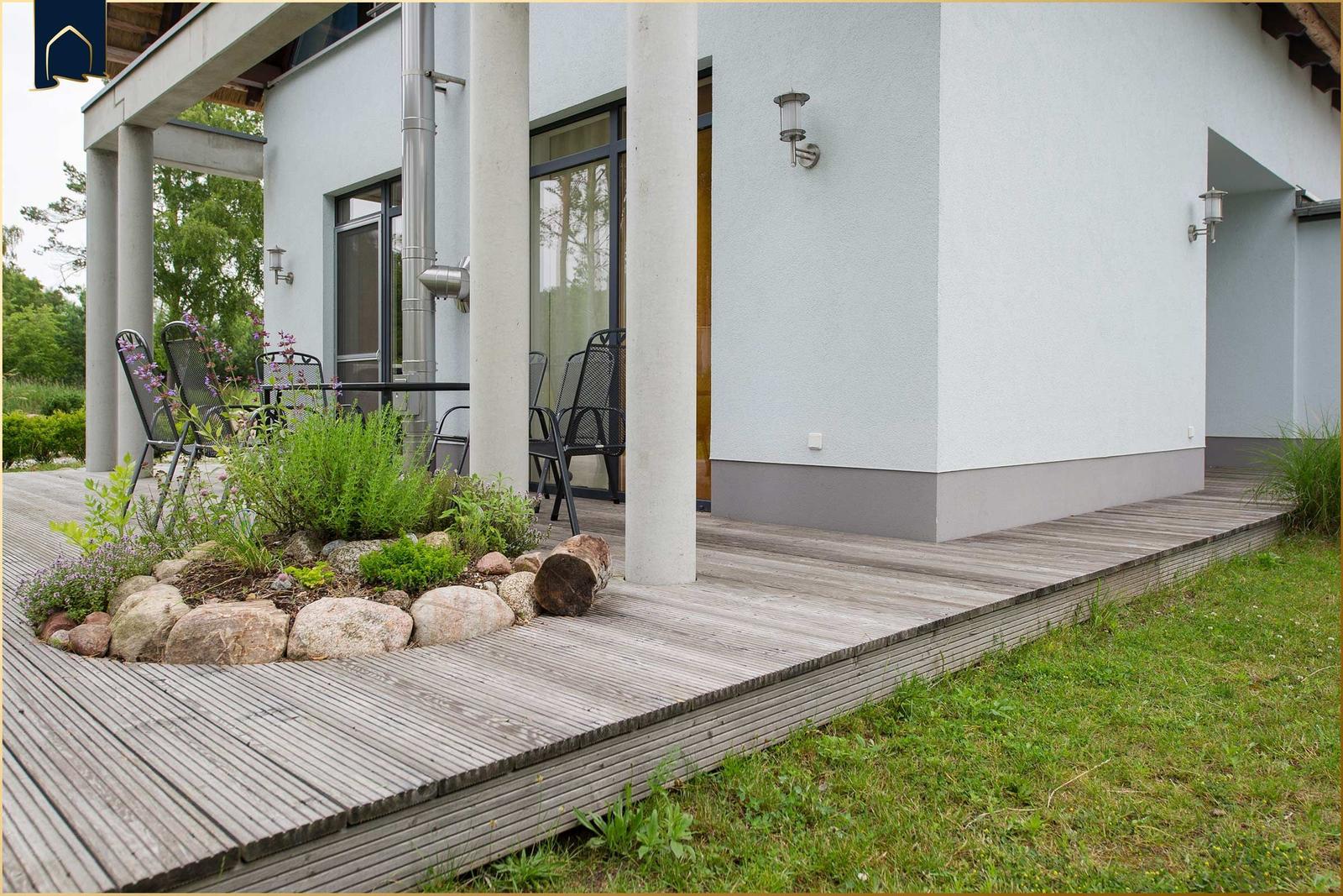 Terrasse mit Sitzgruppe und Pflanzenbeet vor modernem Haus