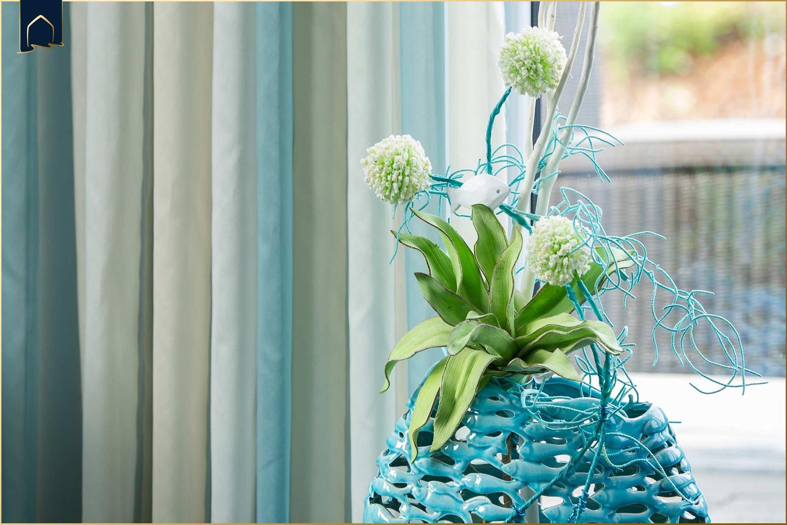 Blauer Vase mit Pflanze und Dekoration vor Fenster