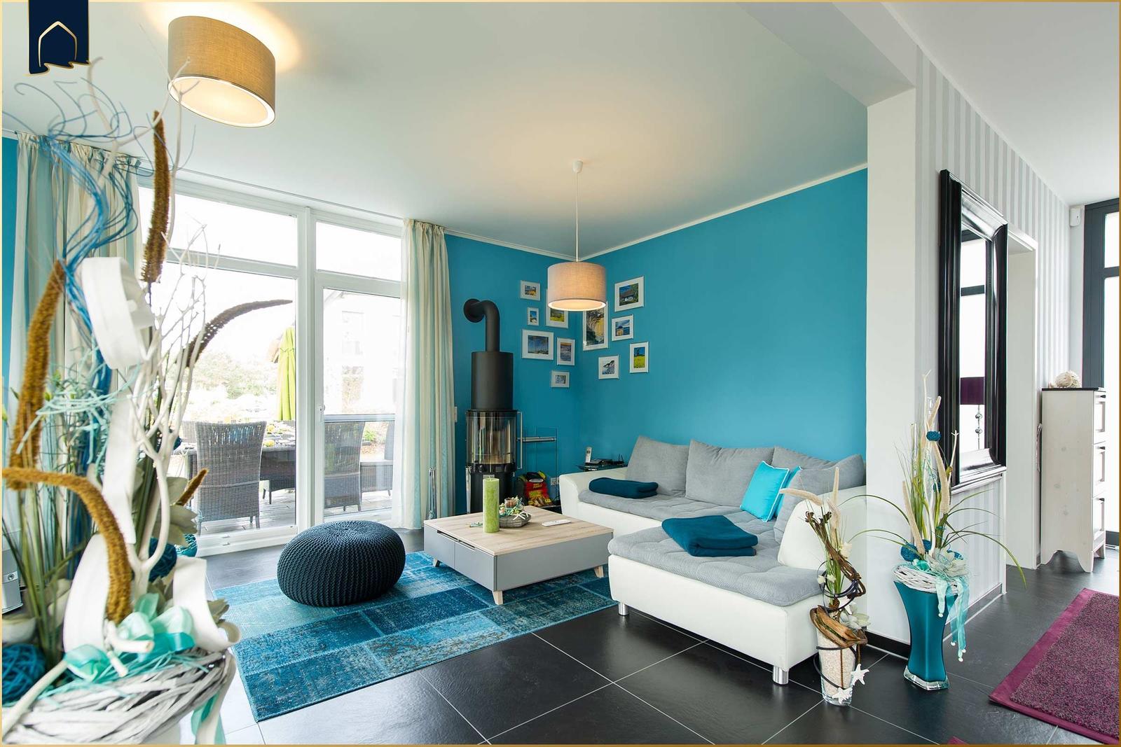 Wohnzimmer mit blauer Wand, Sofa, Kamin und Terrassentür.