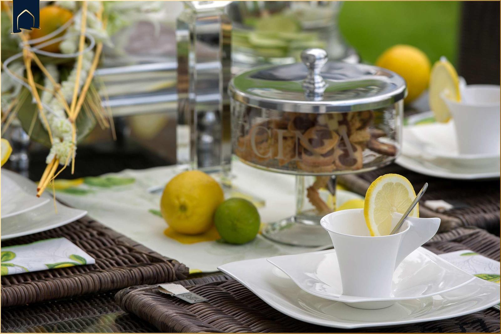 Tisch gedeckt mit Tassen, Zitronen und Keksen in Glasbehälter.