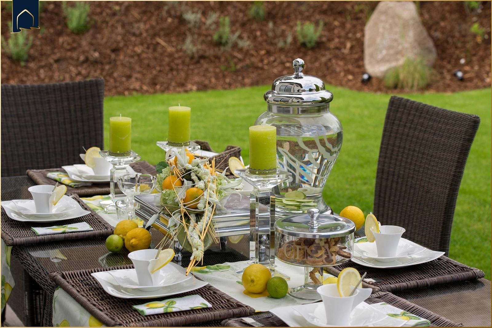 Garten-Tisch mit Tassen, Zitronen und Kerzen für Gäste