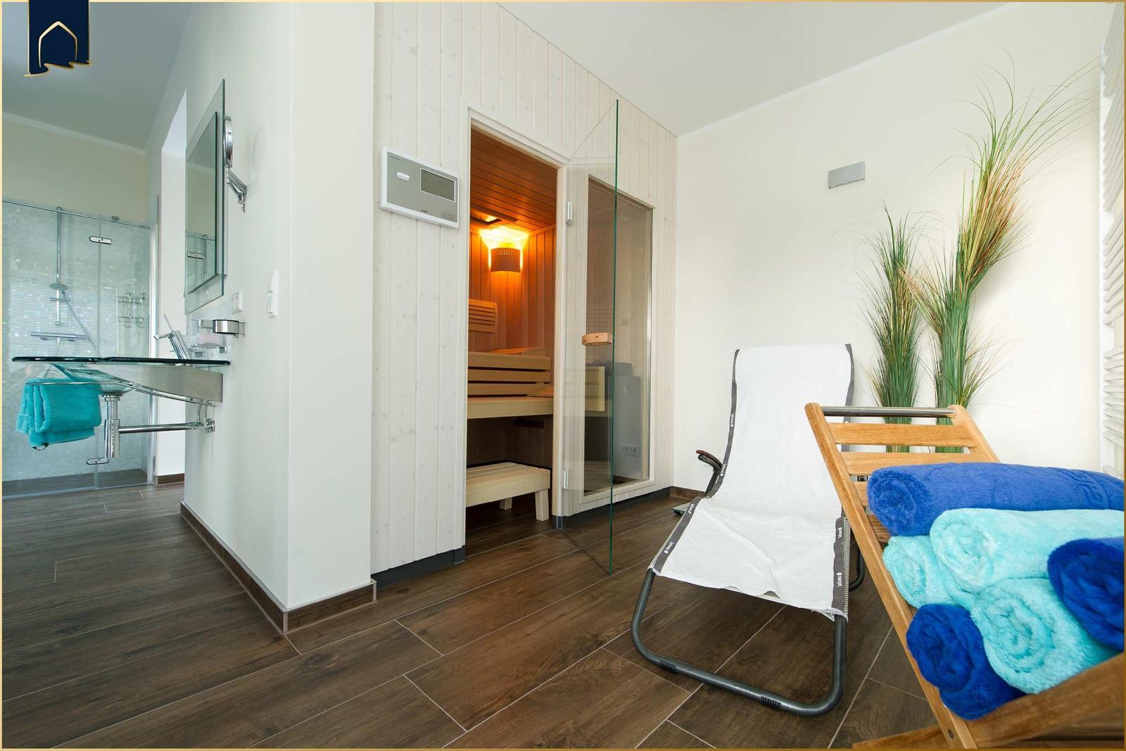 Sauna mit Liegestuhl und Duschbereich mit Glaswand