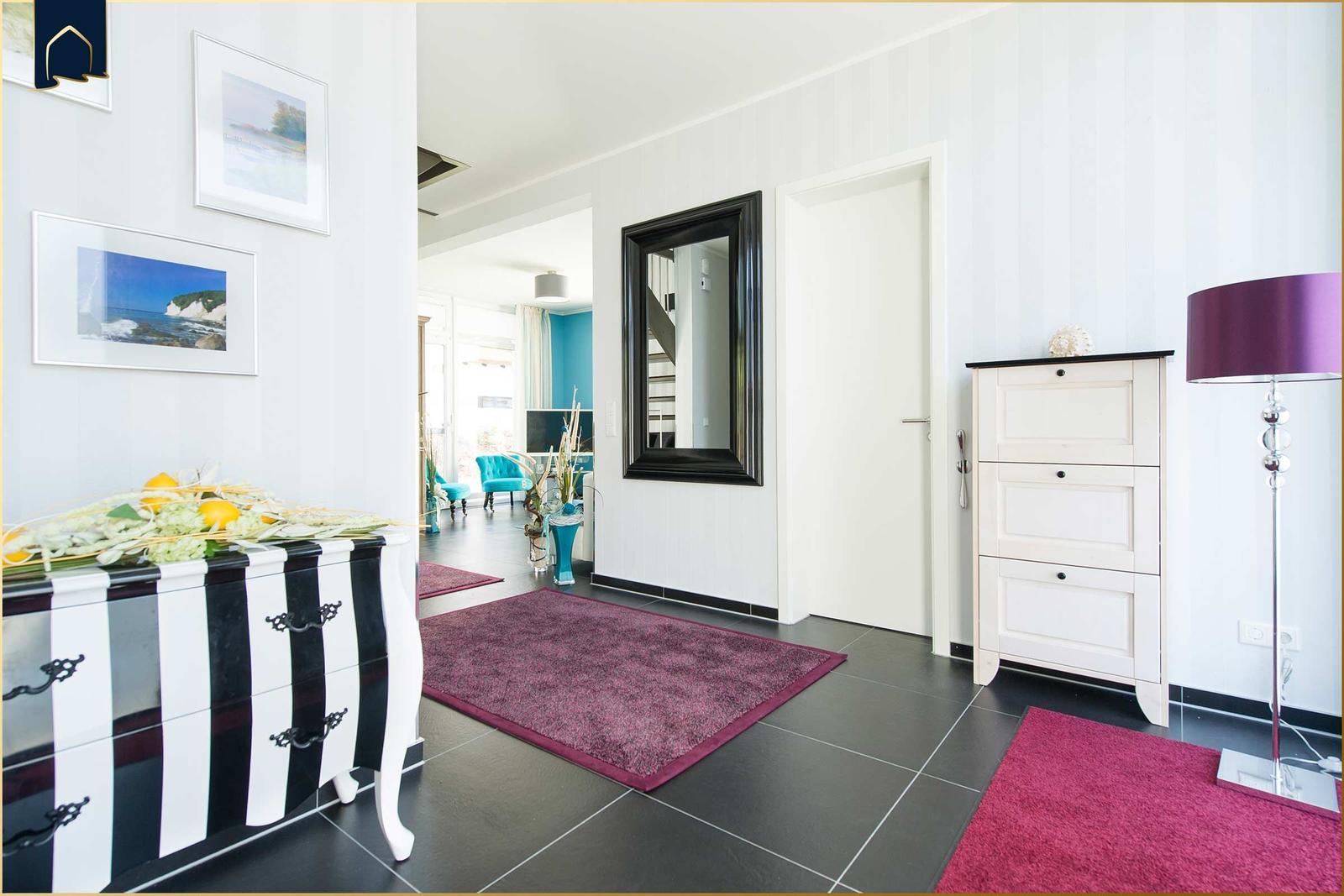 Eingangsbereich mit Schminktisch, Spiegel und Teppichen auf dunklem Boden.