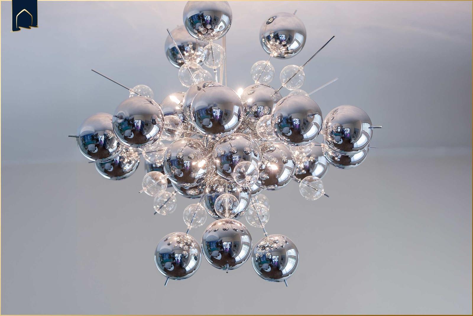 Eine moderne Deckenleuchte mit silbernen Kugeln und Glasbausteinen hängt an der Decke.