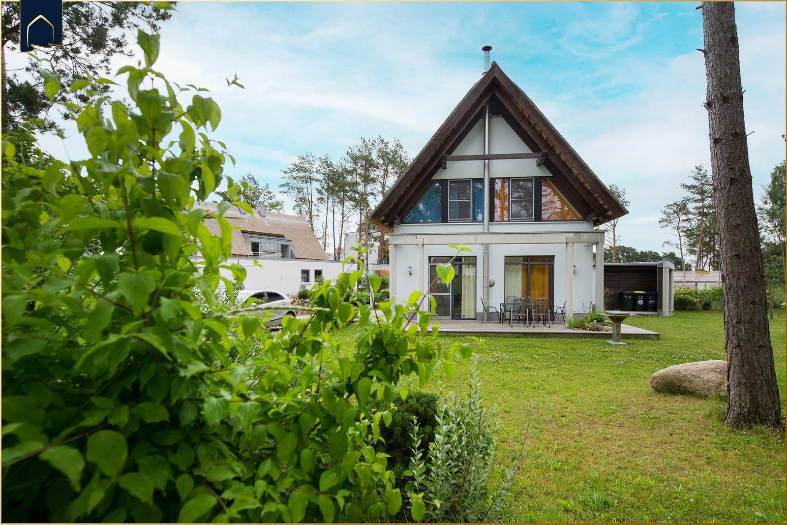 Moderne Villa mit Terrasse und Garten. Umgeben von Bäumen und Grün.