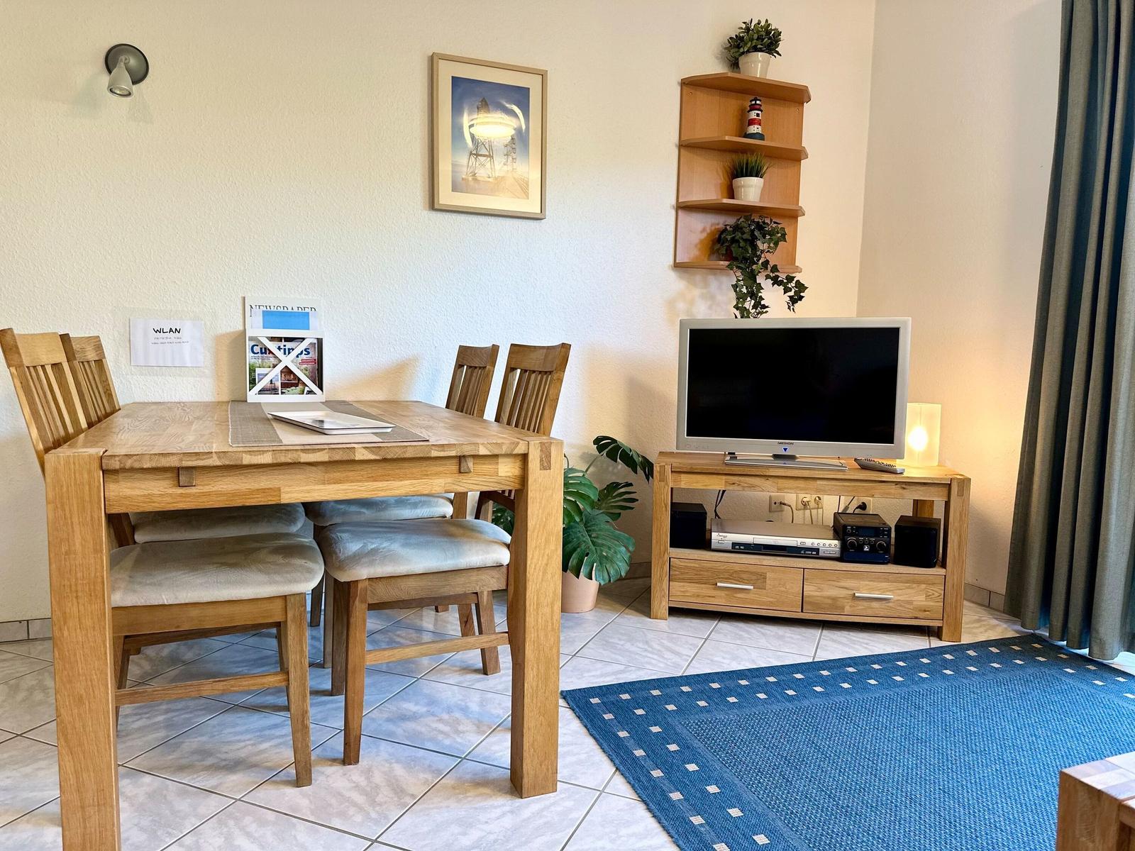 Essbereich mit Holztisch, Fernseher und Blau-Teppich