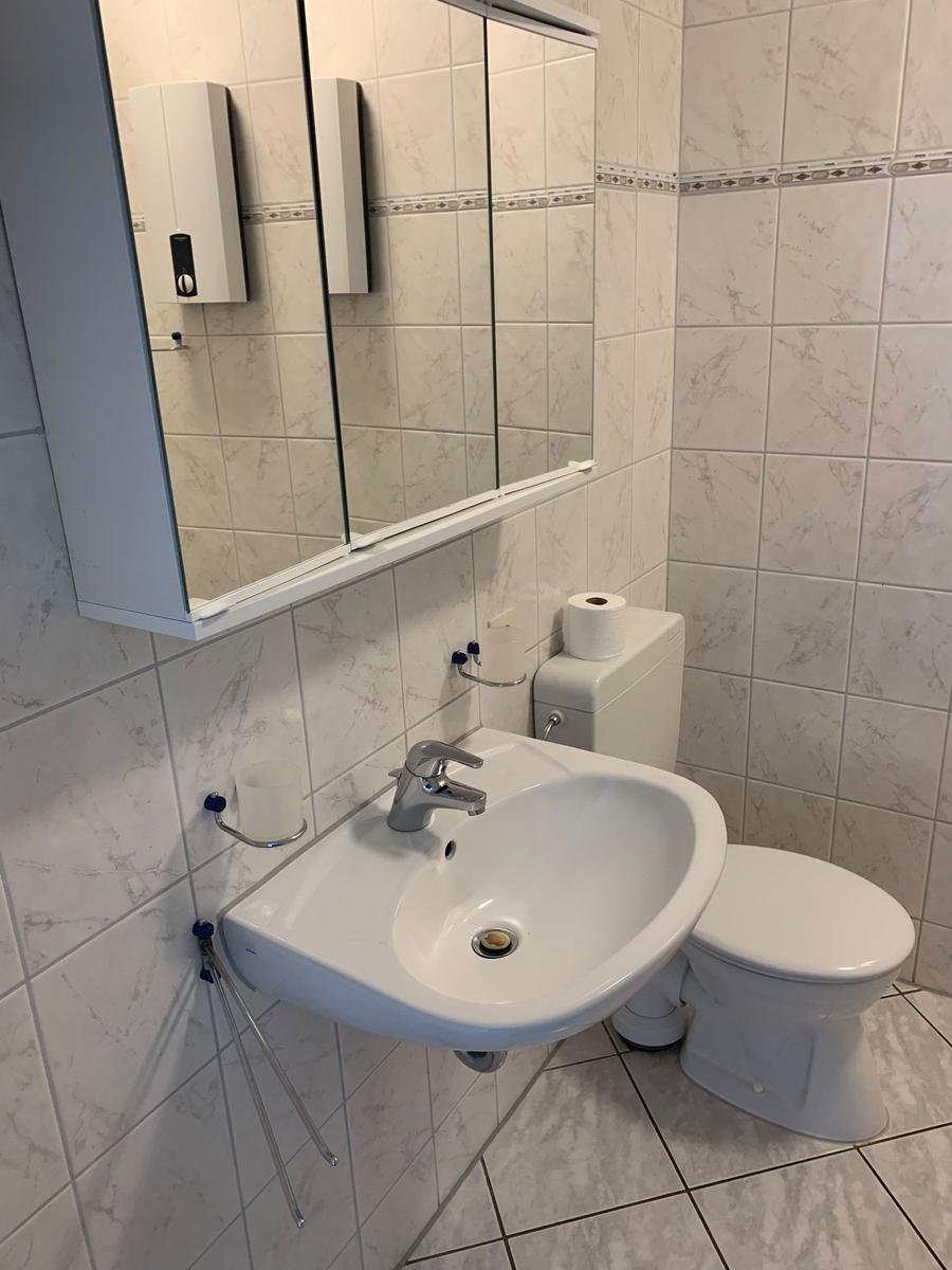 Badezimmer mit Waschbecken, Toilette und Spiegel.