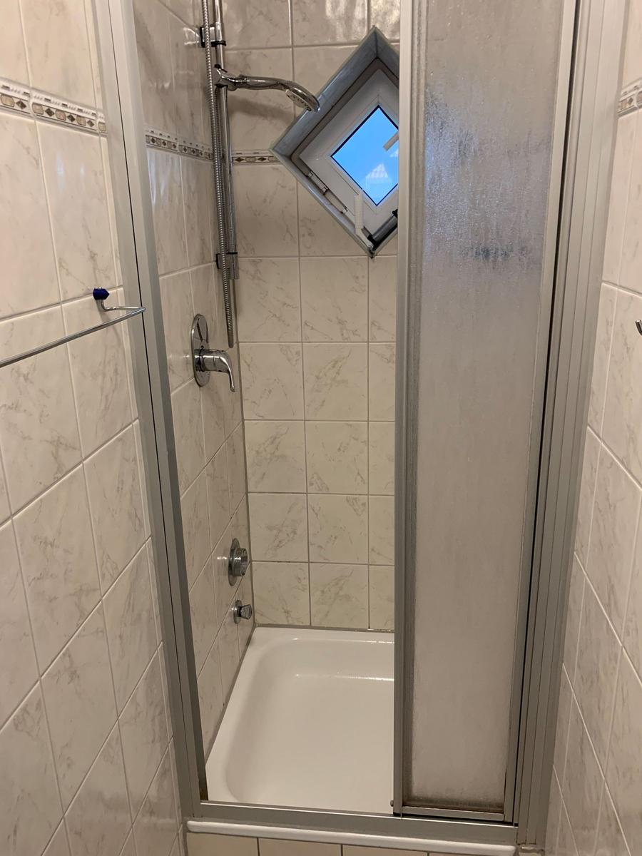 Dusche mit Duschwanne, Duschbrause und Dachfenster.