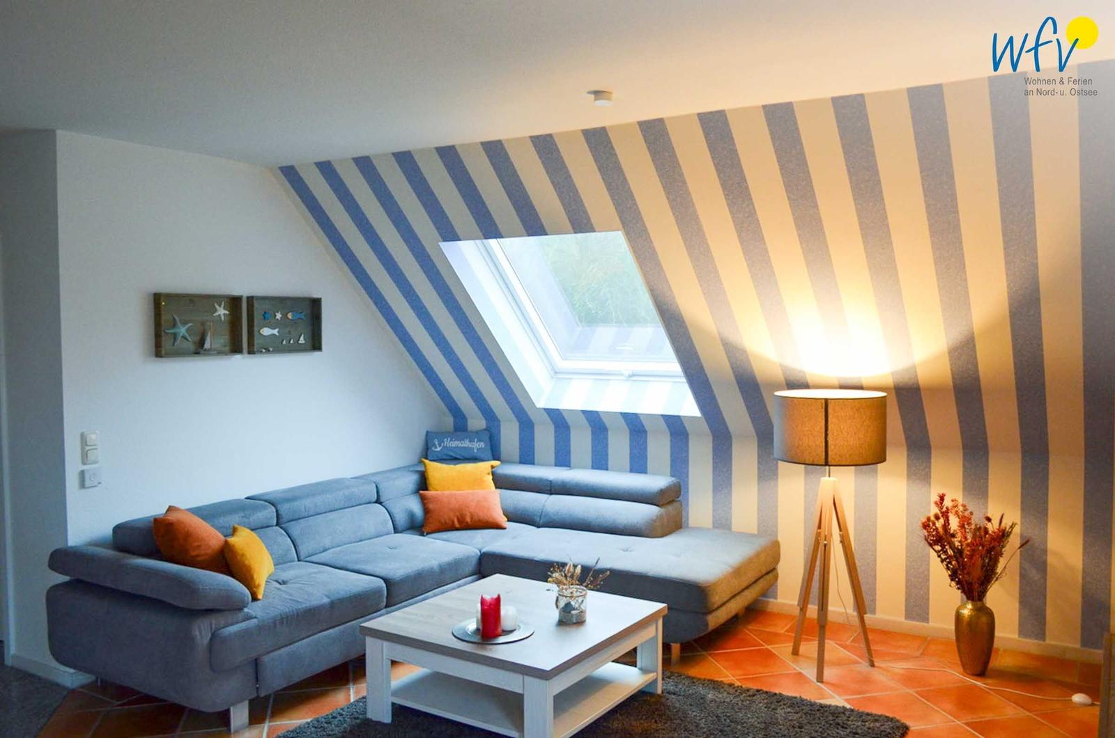 Wohnzimmer mit Sofa, Couchtisch und gestreifter Wand unter Dachschrägen.