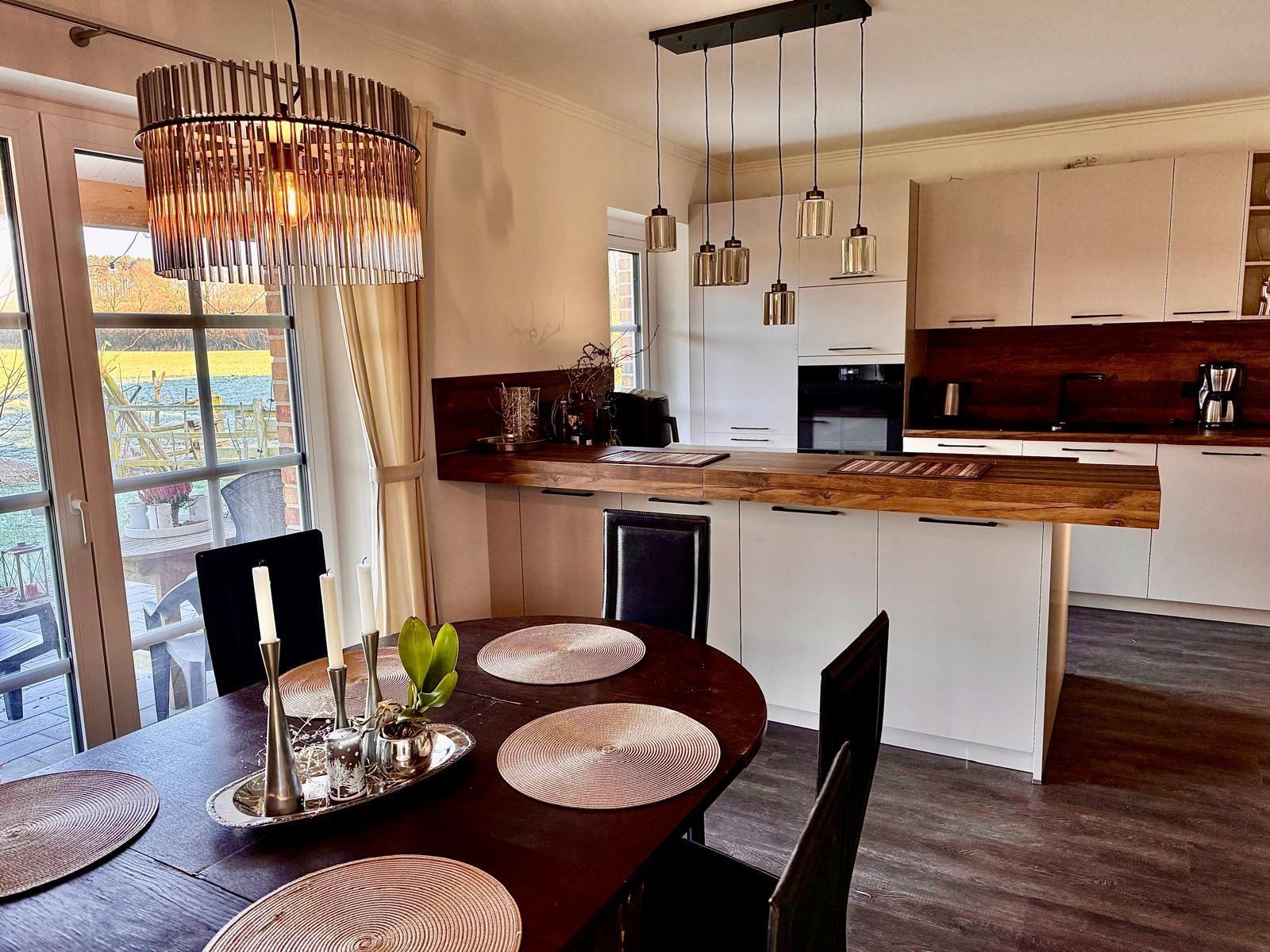 Raum mit gemütlicher Sitzecke und 65 Zoll TV Offener Küche mit Tresen und Kochinsel. Essecke mit 6 Plätzen. Blick auf die Felder. und d...