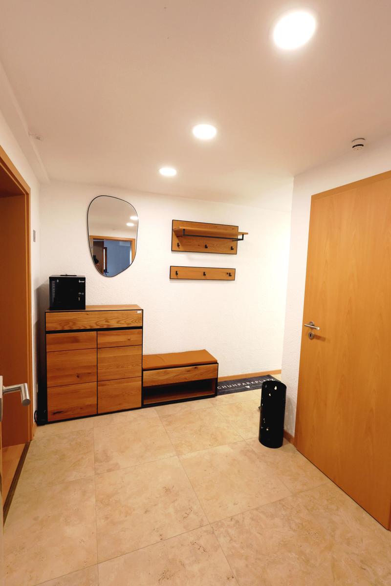 Eingangsbereich mit Holzmöbeln, Spiegel und Hakenwand.