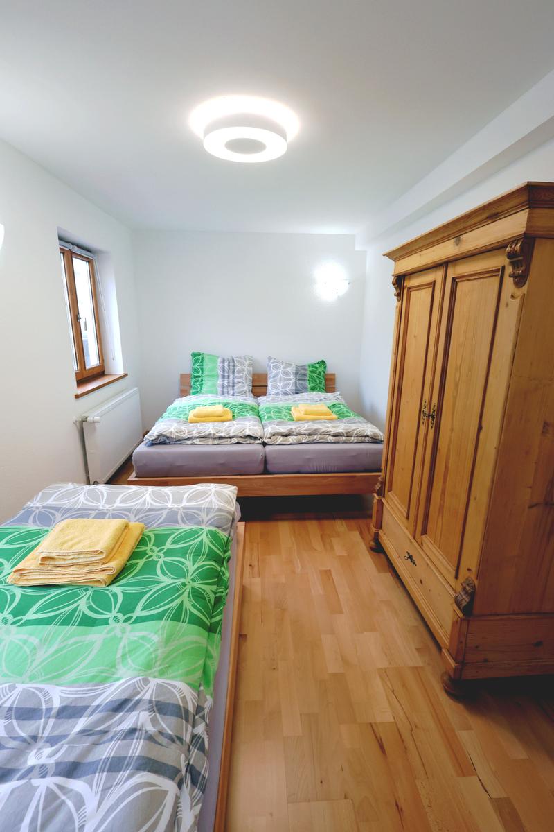 Zimmer mit zwei Betten, Holzschrank und Fenster.