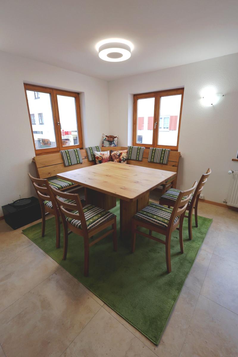 Esszimmer mit Holztisch, Sitzbank und Stühlen auf grünem Teppich