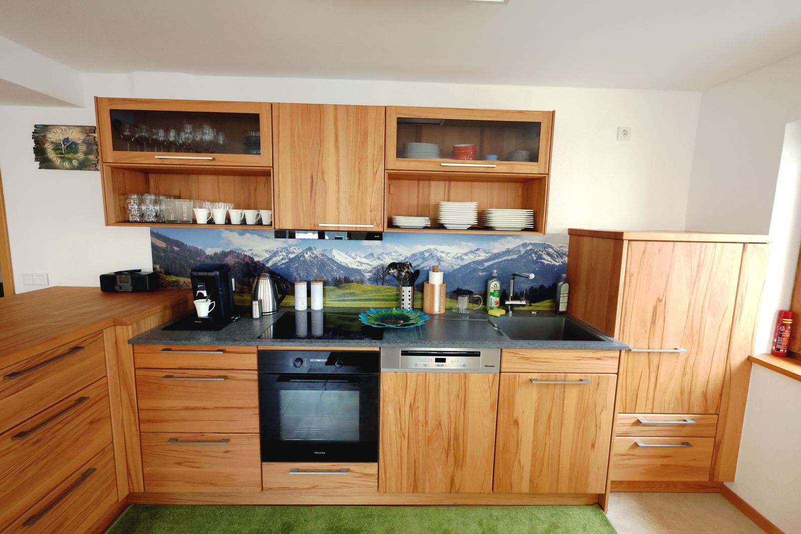 Küche mit Holzschränken, Steinplatte und Bergmotivwand