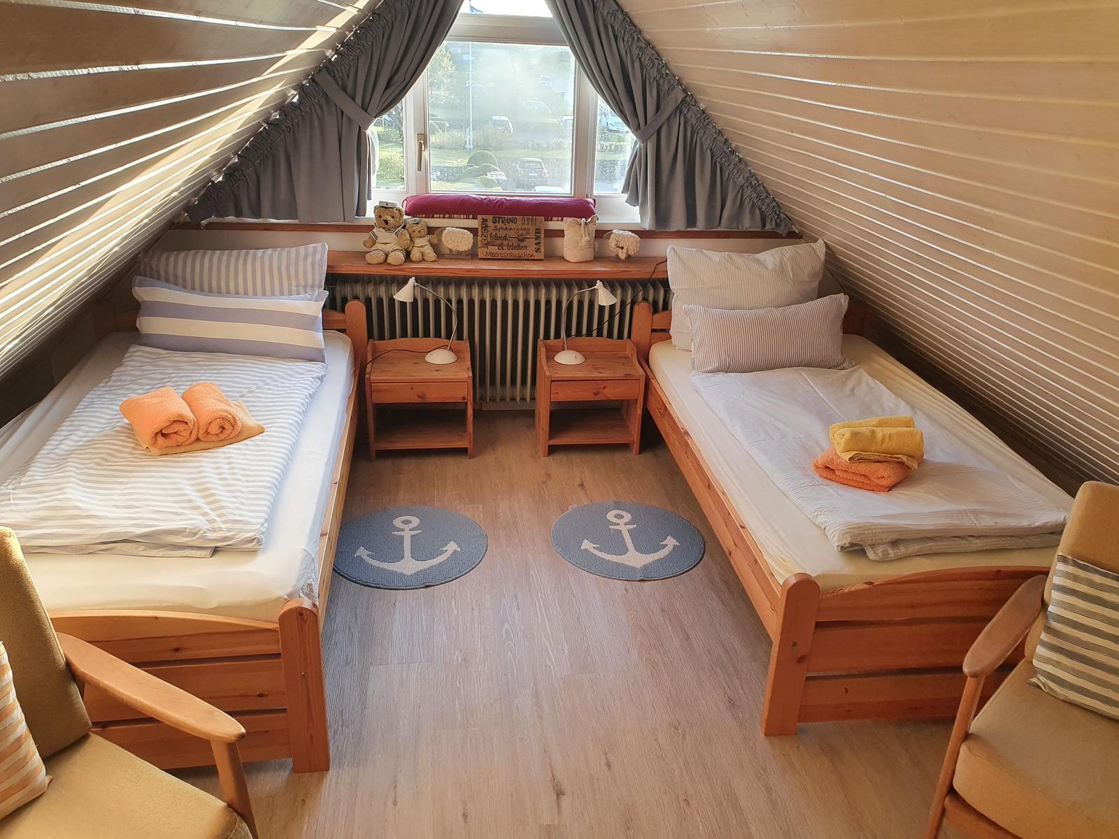 Zwei Einzelbetten mit Handtüchern, Holzmöbel und Fenster mit Blick.