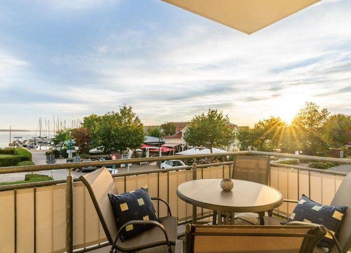 Balcony with table and chairs overlooking marina and sunset.