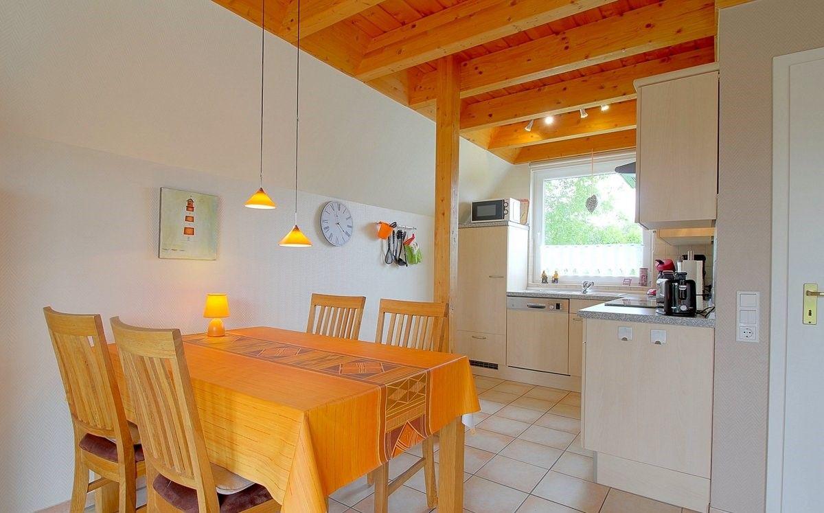 Essbereich mit Tisch und Stühlen, Küche mit Küchenzeile und Fenster.