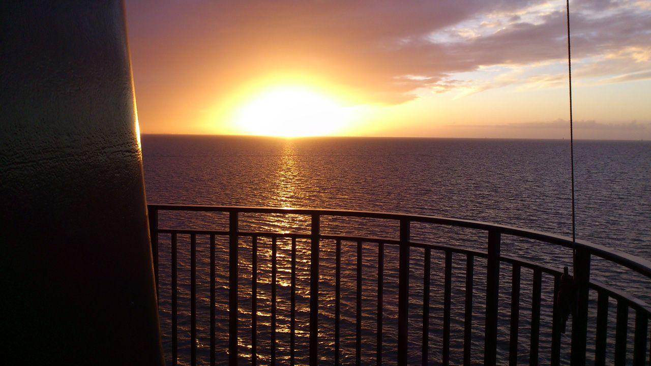 Sonnenuntergang über dem Meer von einer Balkonterrasse aus gesehen.
