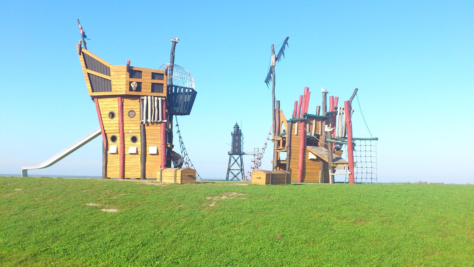 Großes Spielgelände mit Piratenschiff und Klettergerüst auf grünem Rasen.