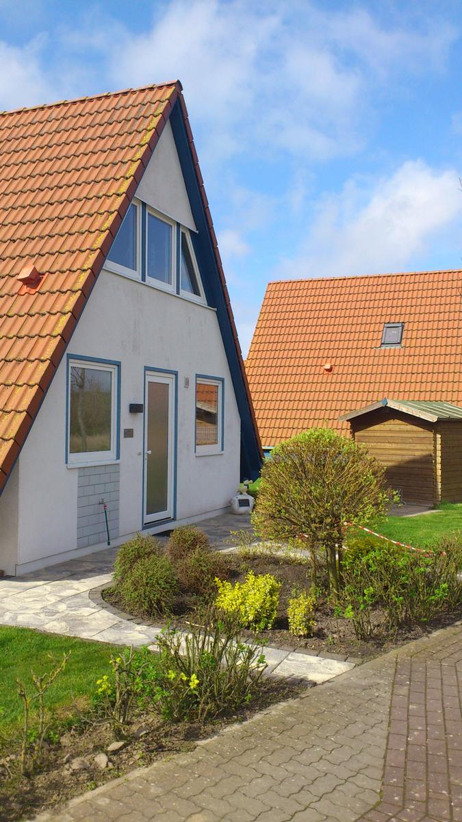 Wohnhaus mit Terrasse und Garten. Hinterhof mit Holzgarage und Rasenfläche.