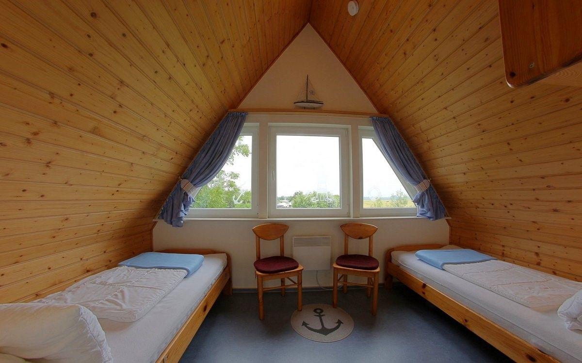 Zimmer mit zwei Betten, Holzwand und Fenster mit Blick nach draußen.