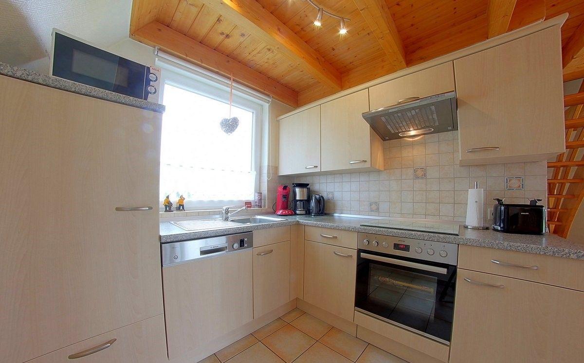 Küche mit Holzdecke, hellen Schränken und moderner Ausstattung.