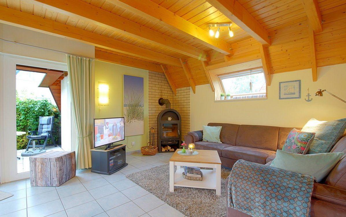 Wohnzimmer mit Holzdecke, Sofa, Fernseher und Kaminofen.