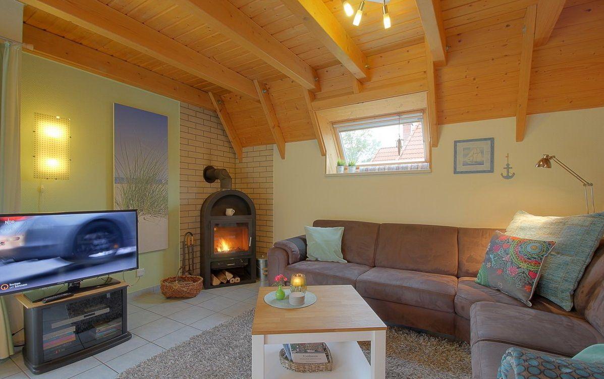 Wohnzimmer mit Sofa, Kamin und Fernseher unter Holzbalkendecke