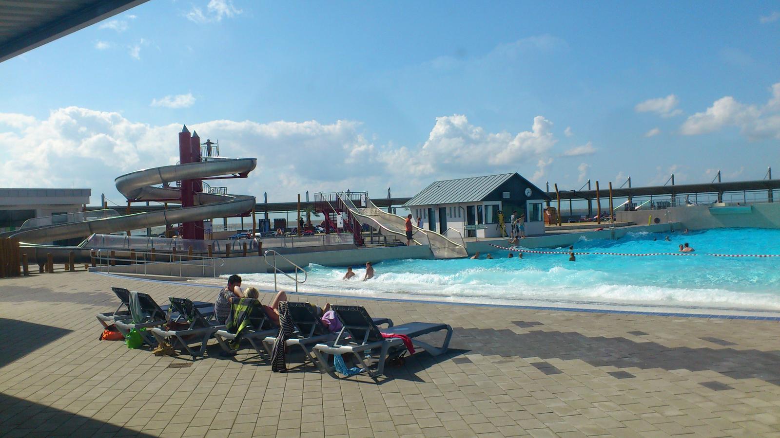 Pool mit Rutschen und Liegestühlen unter blauem Himmel
