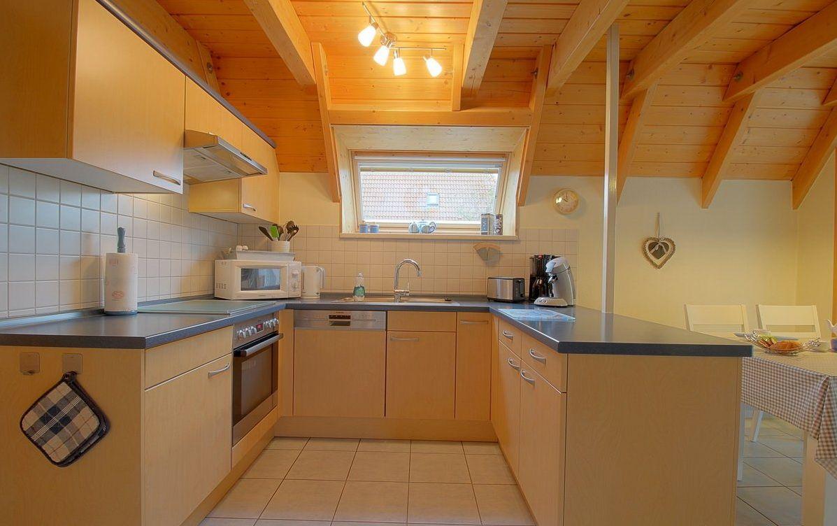 Küche mit Holzbalkendecke, Arbeitsplatten und Küchengeräten.