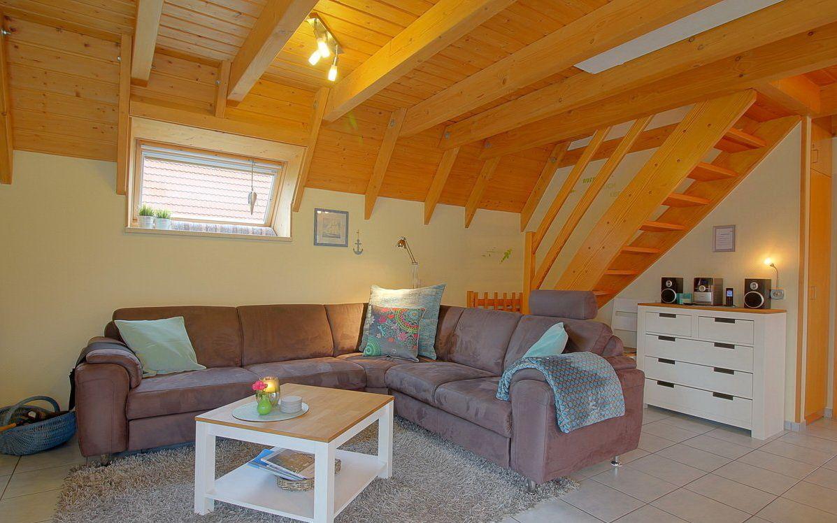 Wohnzimmer mit Sofa, Couchtisch und Holzdecke. Treppenhaus zur Unterkunft.