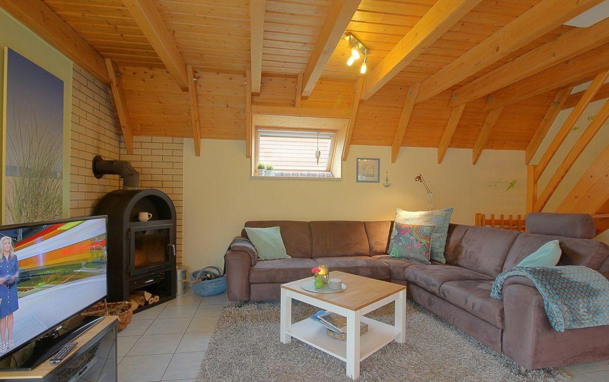 Wohnzimmer mit Sofa, Kamin und Holzdecke.