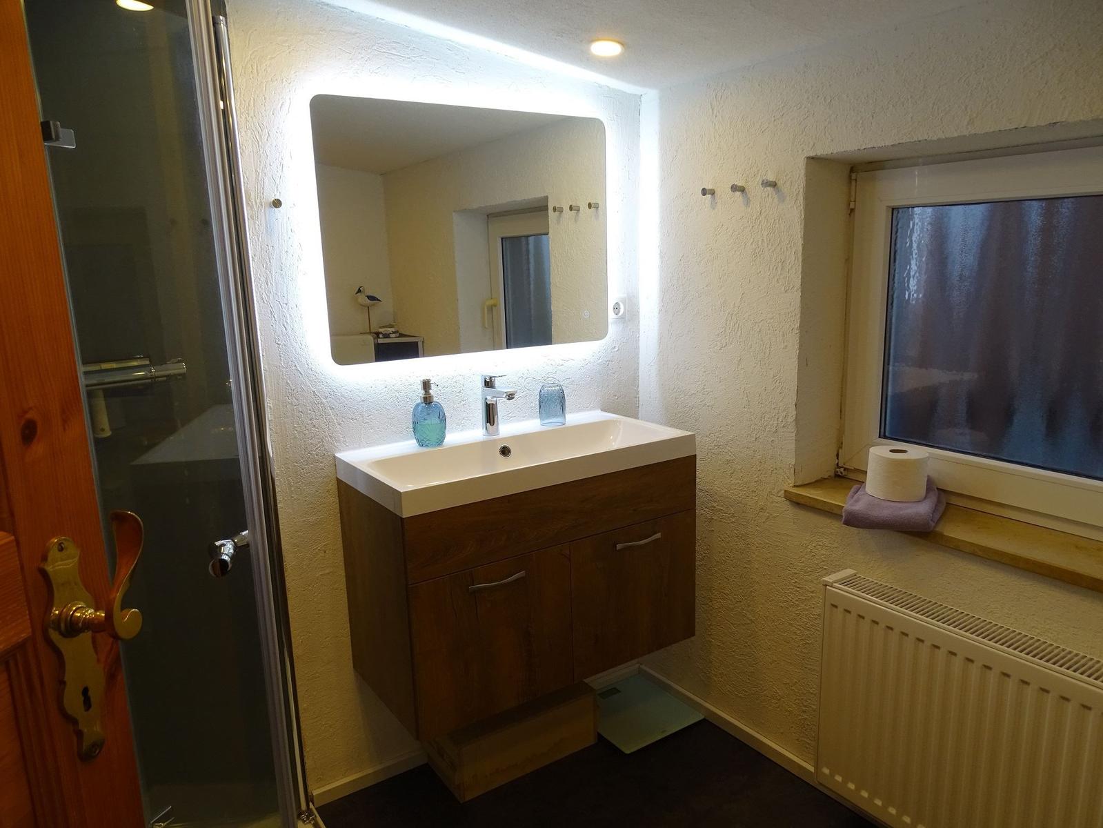 Badezimmer mit Waschbecken, Spiegel und Dusche.