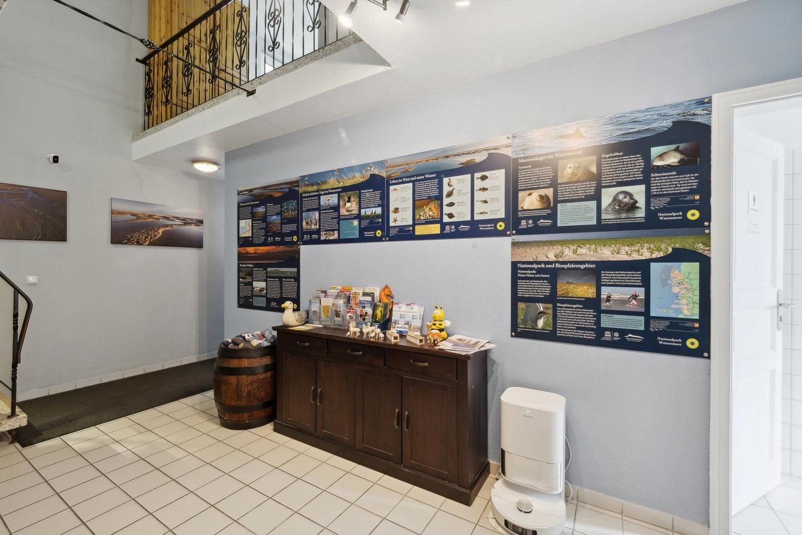 Wohnung mit Informationswänden über Nationalpark Wattenmeer und Holzgeländer im Obergeschoss.