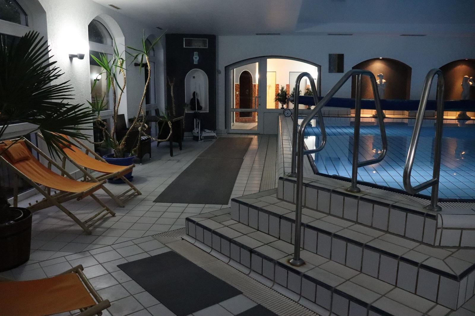 Innenpool mit Liegestühlen und Pflanzen. Treppen zum Einsteigen. Hintergrund mit Badebereich.