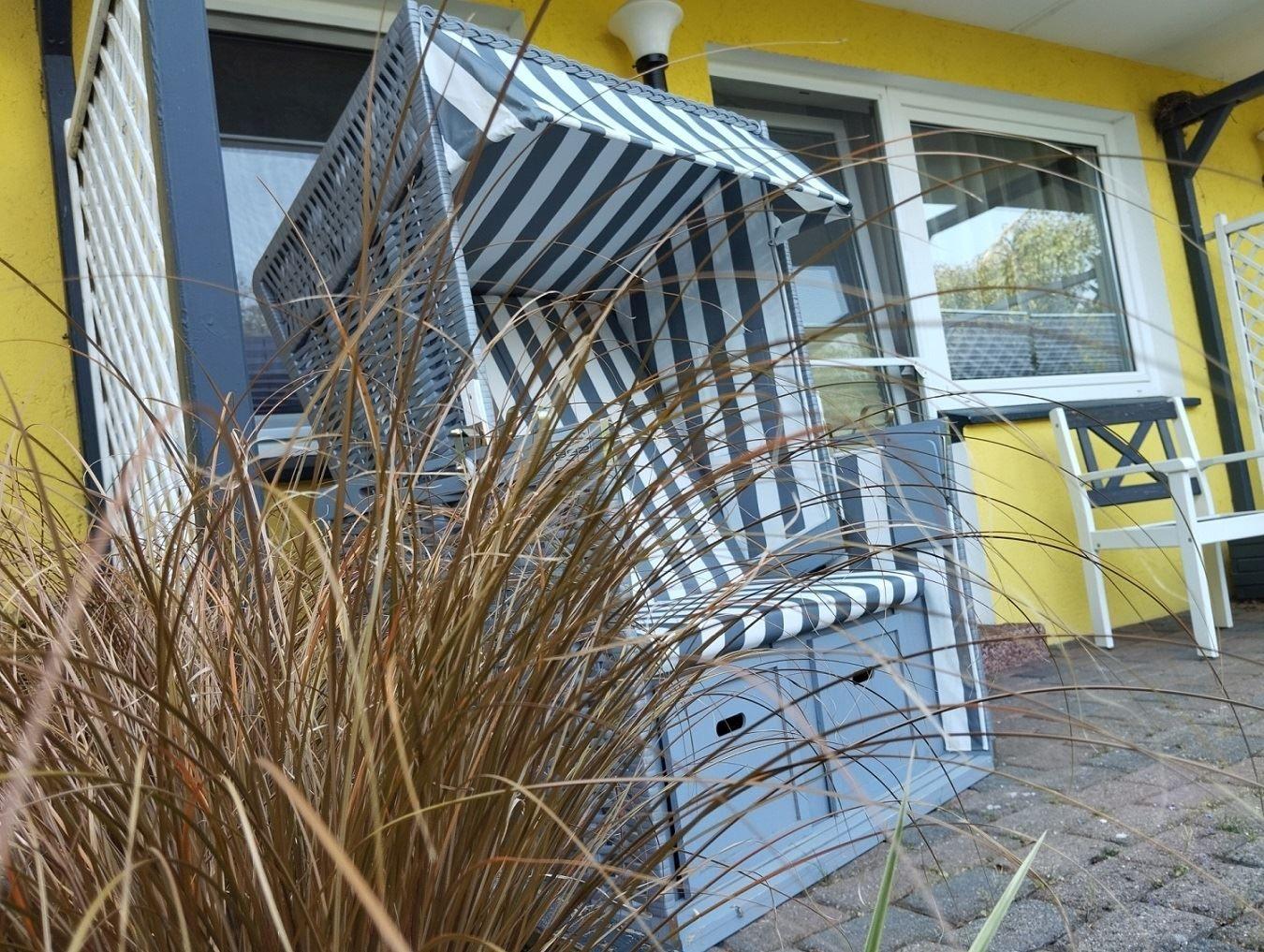 Strandkorb mit Streifen vor gelbem Haus und Pflanzen